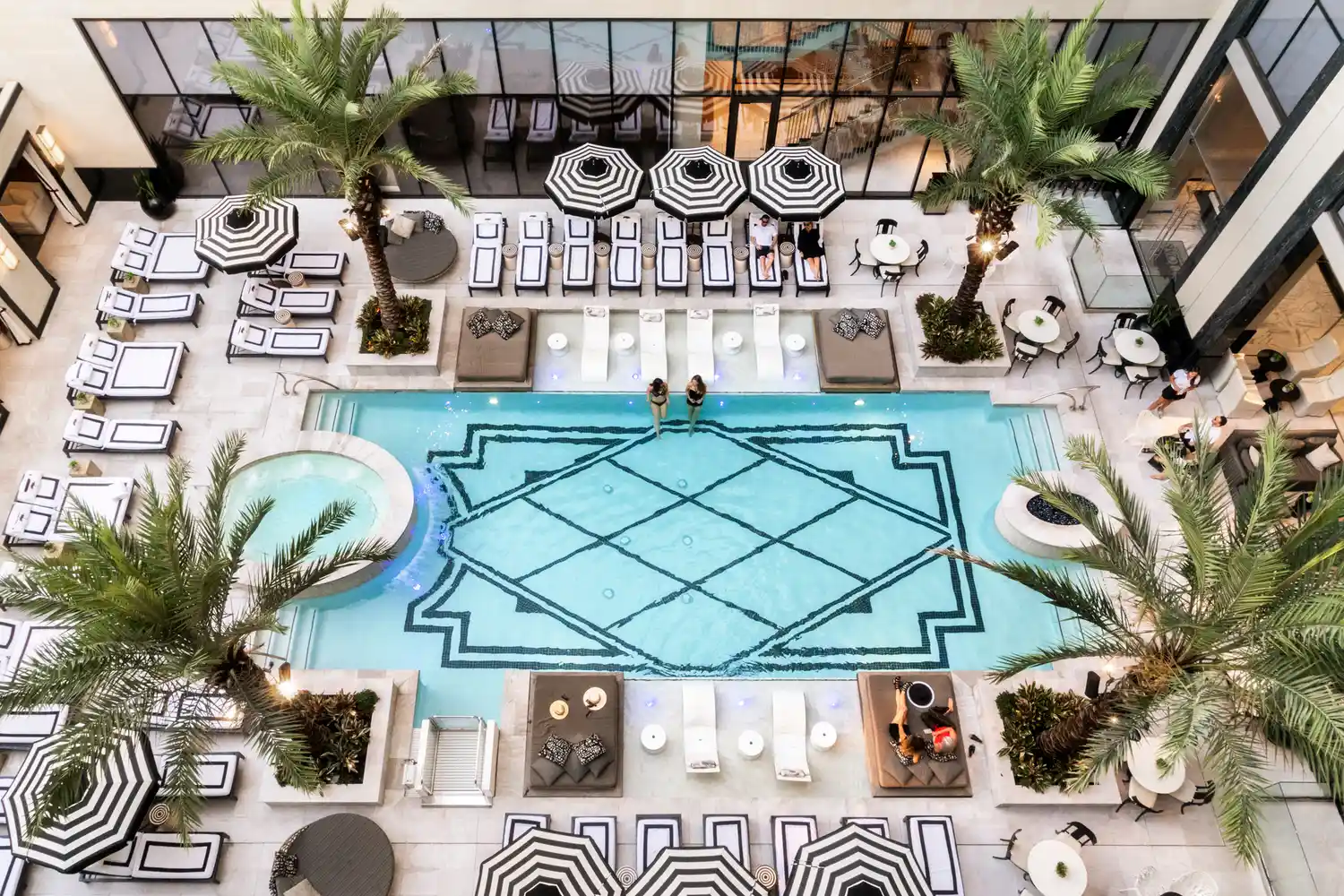 Aerial view of the luxury pool at The Post Oak Hotel in Houston featuring palm trees and lounge chairs.