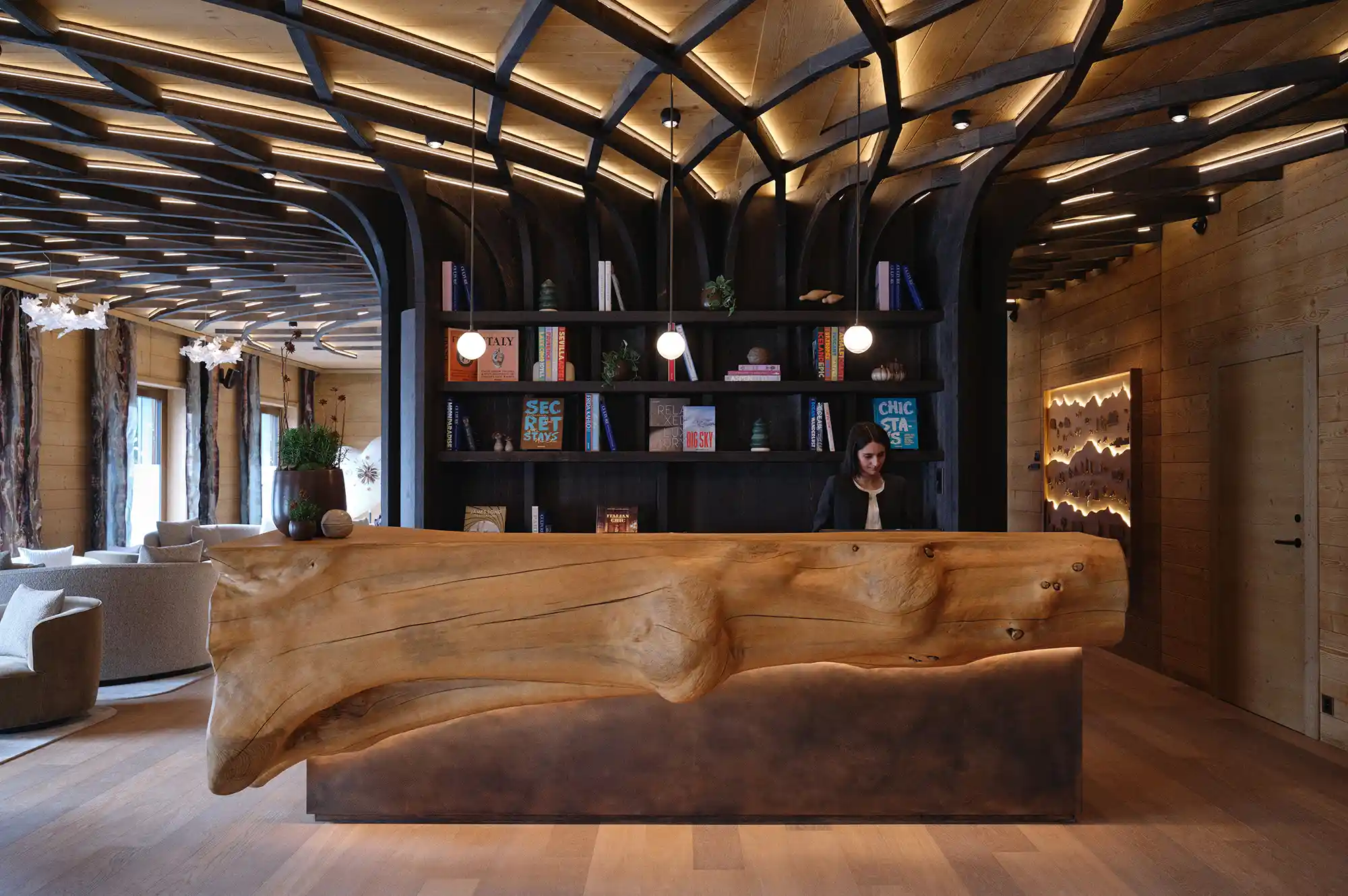 Modern hotel reception desk with floor-to-ceiling wooden bookshelves and minimalist timber design.
