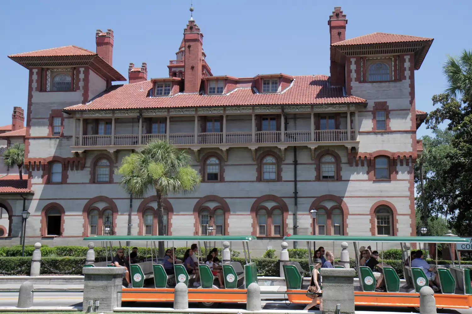 The green and orange Old Town Trolley passing by the ornate Spanish Renaissance architecture of Flagler College.
