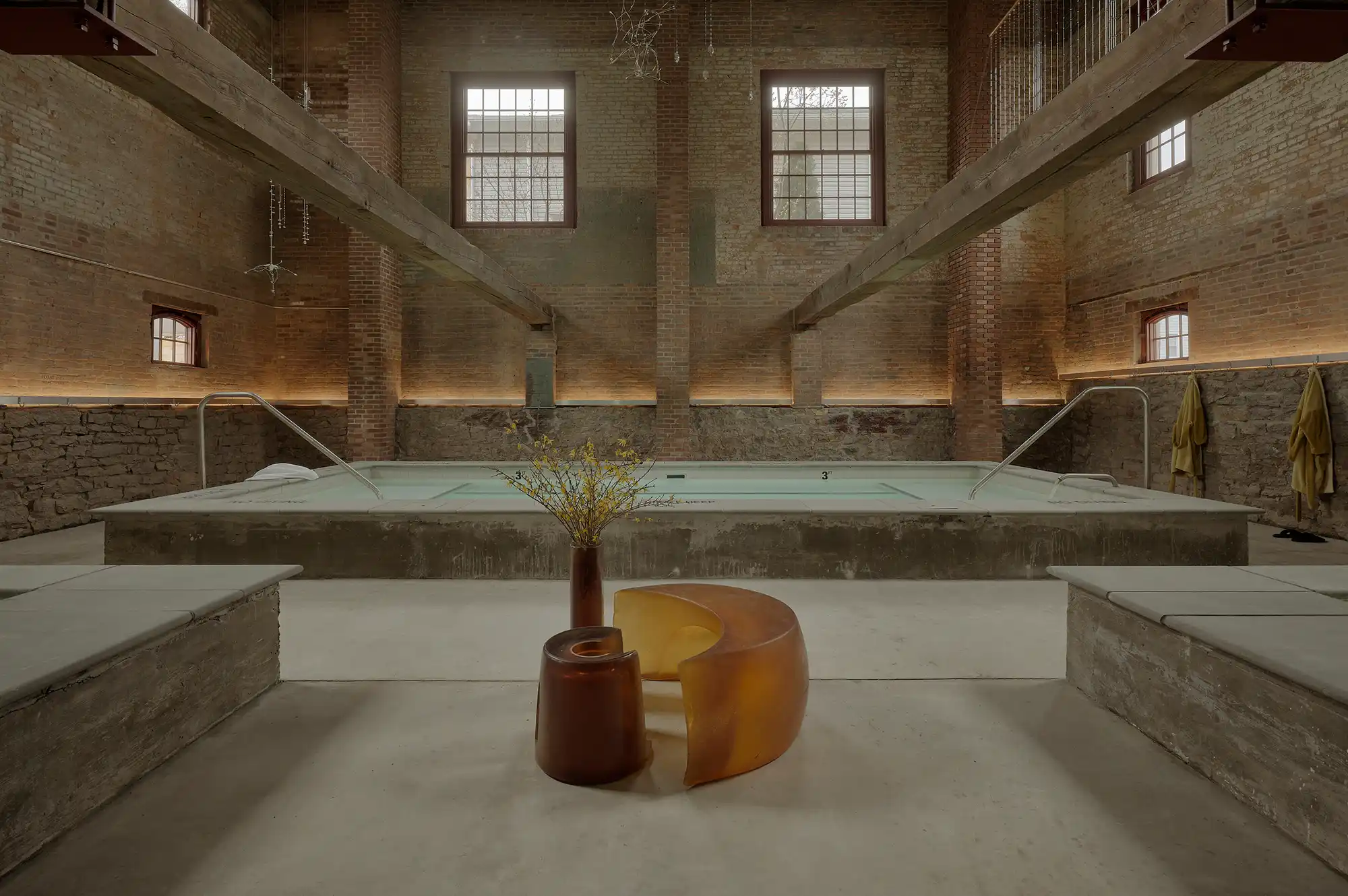 Subterranean spa pool at the Baths in Pocketbook Hudson with soft lighting and brick walls.