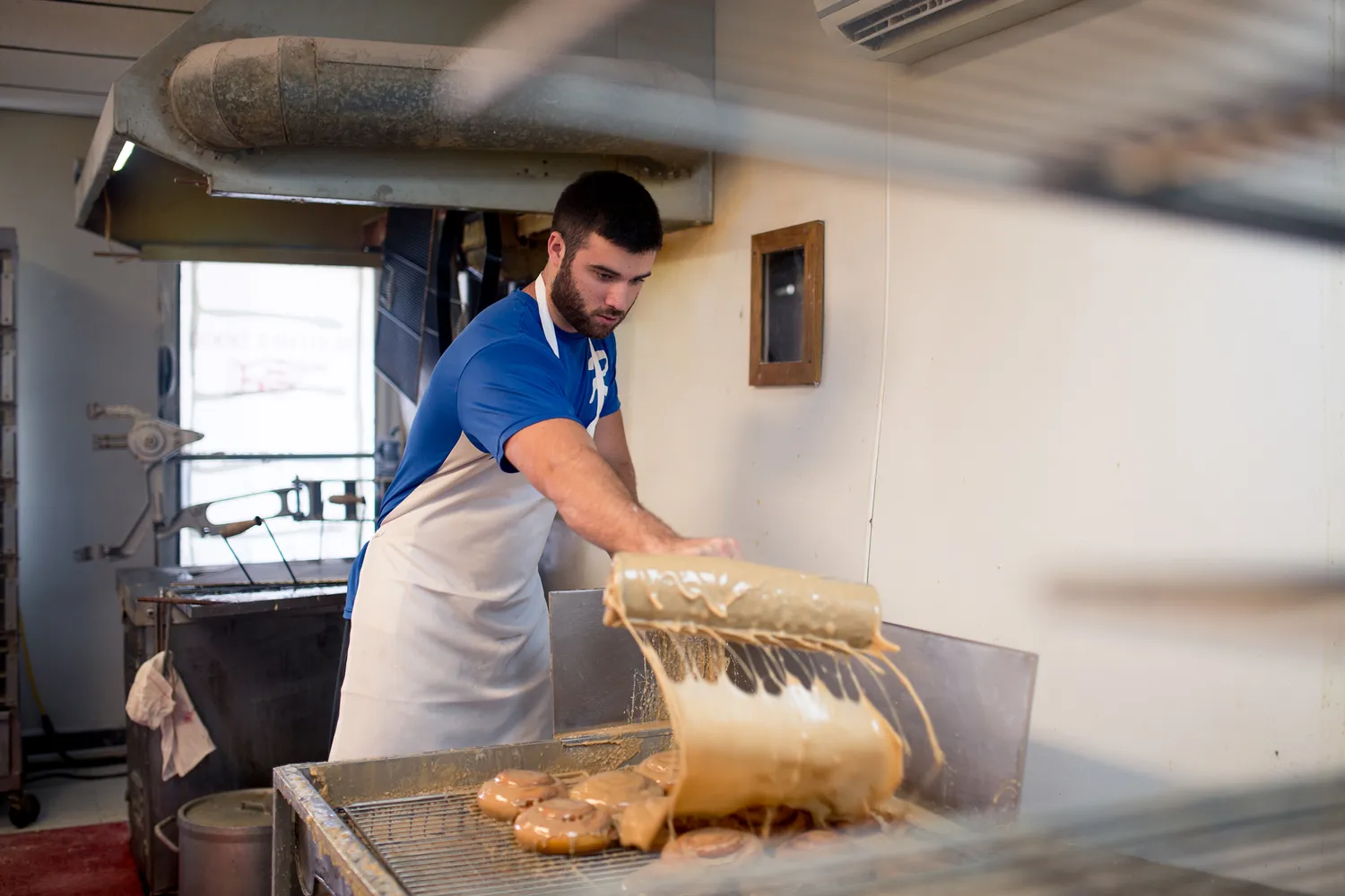 Close-up of a tray of donuts being glazed by a baker at Ralph's Donut Shop.