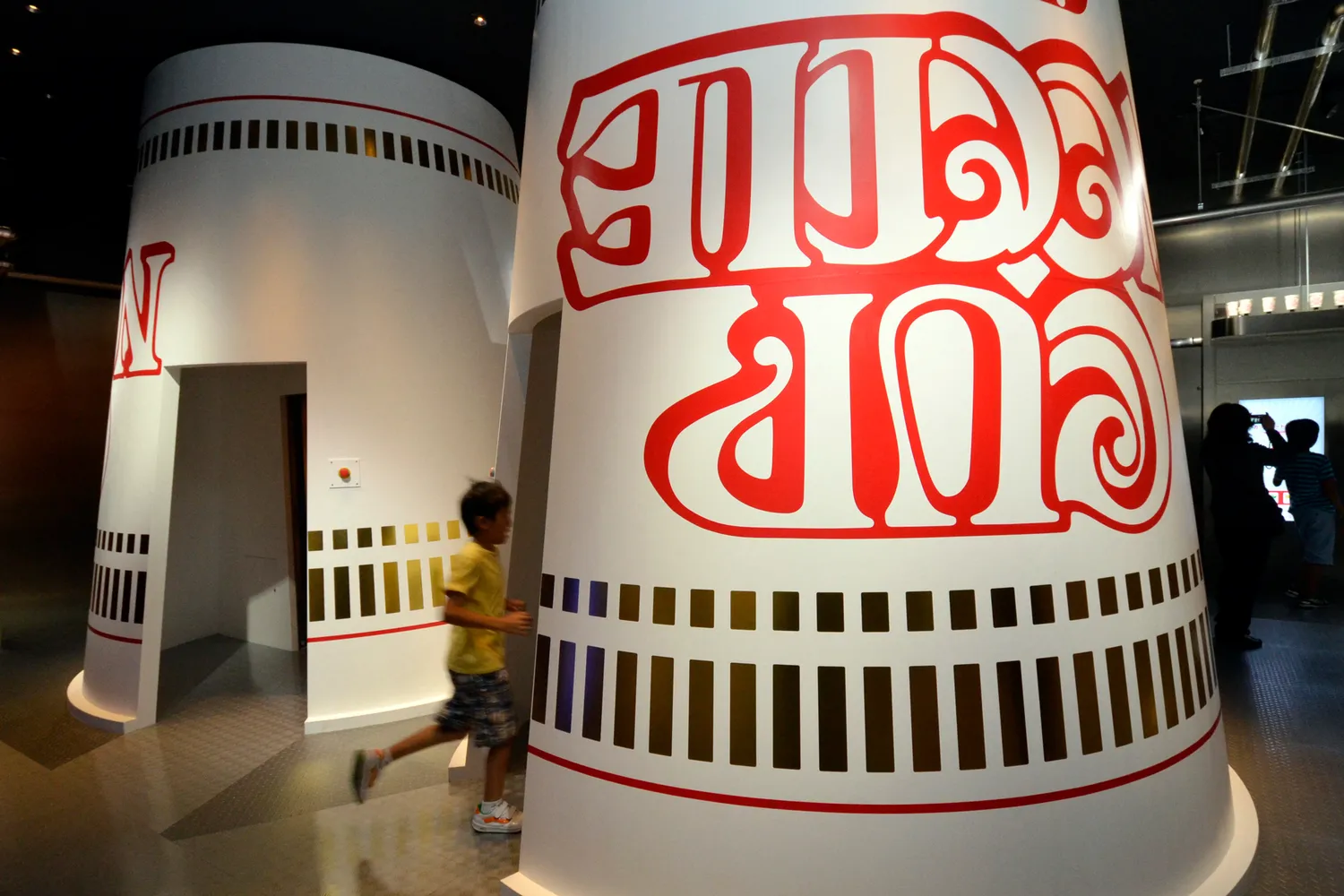 Giant Cup Noodles art installations inside a high-ceilinged museum hall.
