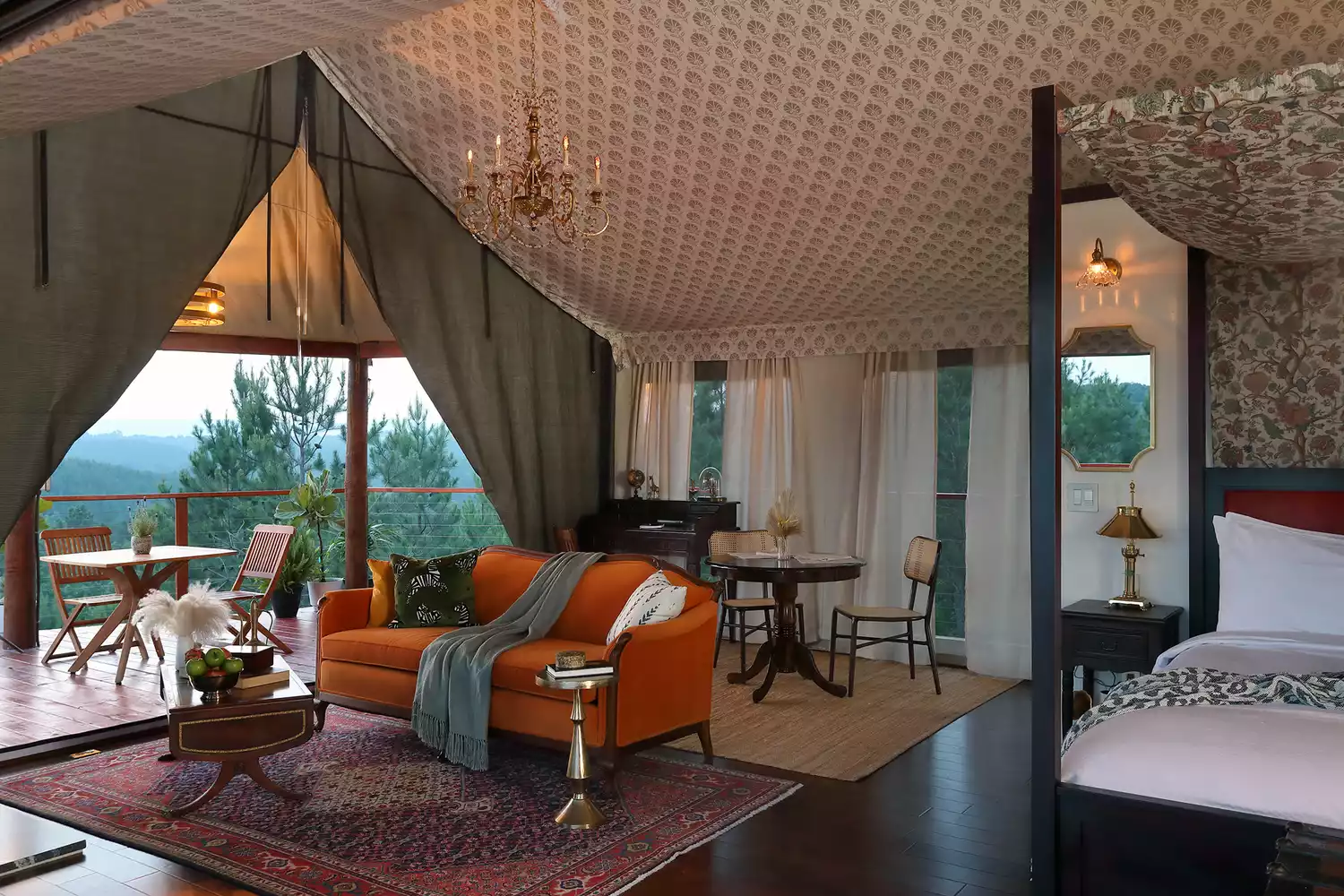 The bohemian-style interior of a glamping tent featuring a four-poster bed and curated furniture.