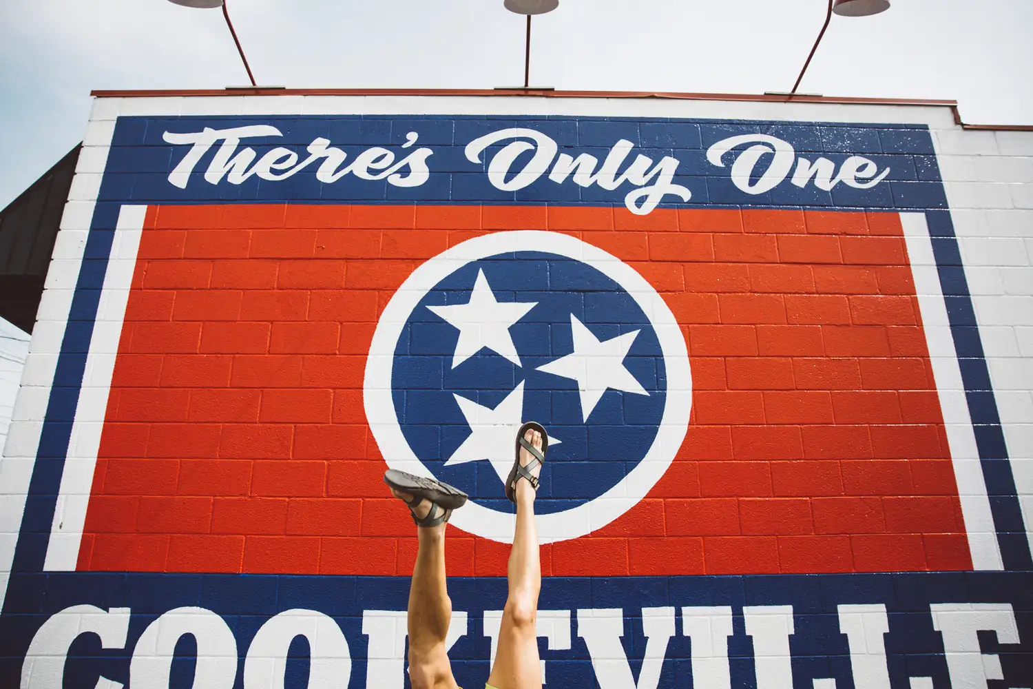 Close-up of the 'There's Only One Cookeville' mural with a person showing feet in front of it.