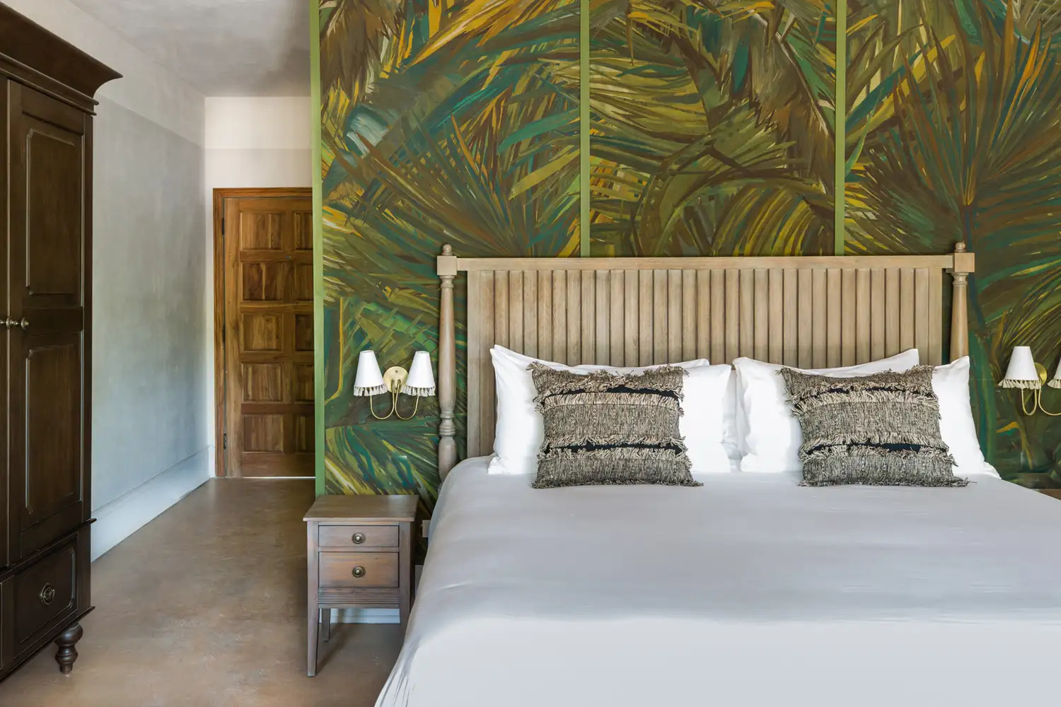 A guest suite featuring tropical wall art and artisanal wooden furniture.
