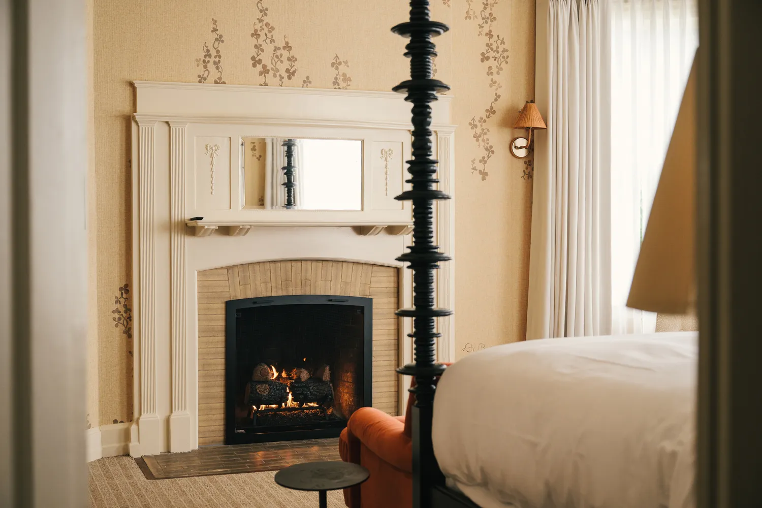 An elegant guest room featuring a classic fireplace and four-poster bed.