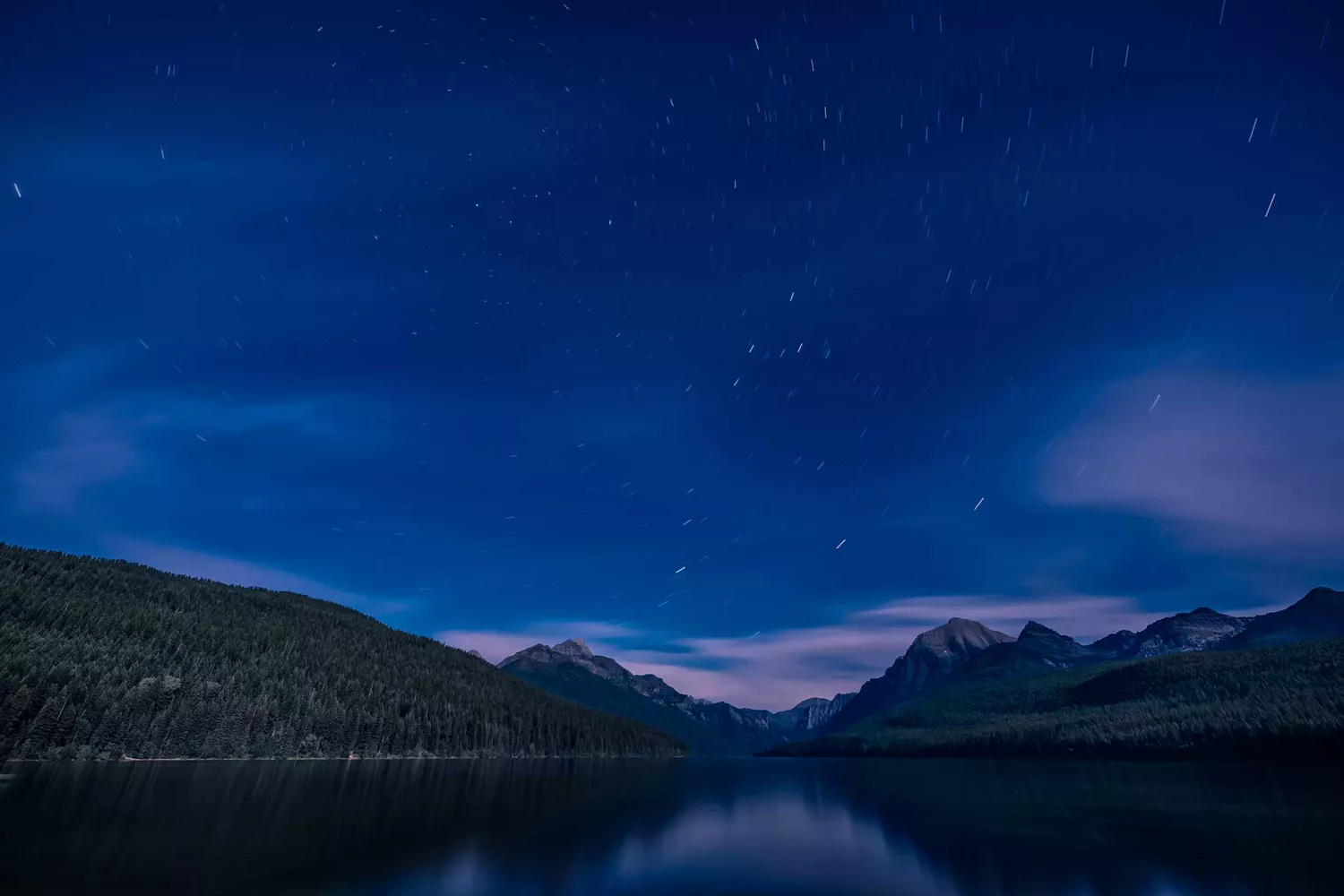 Star trails forming concentric circles over Bowman Lake in Glacier National Park.