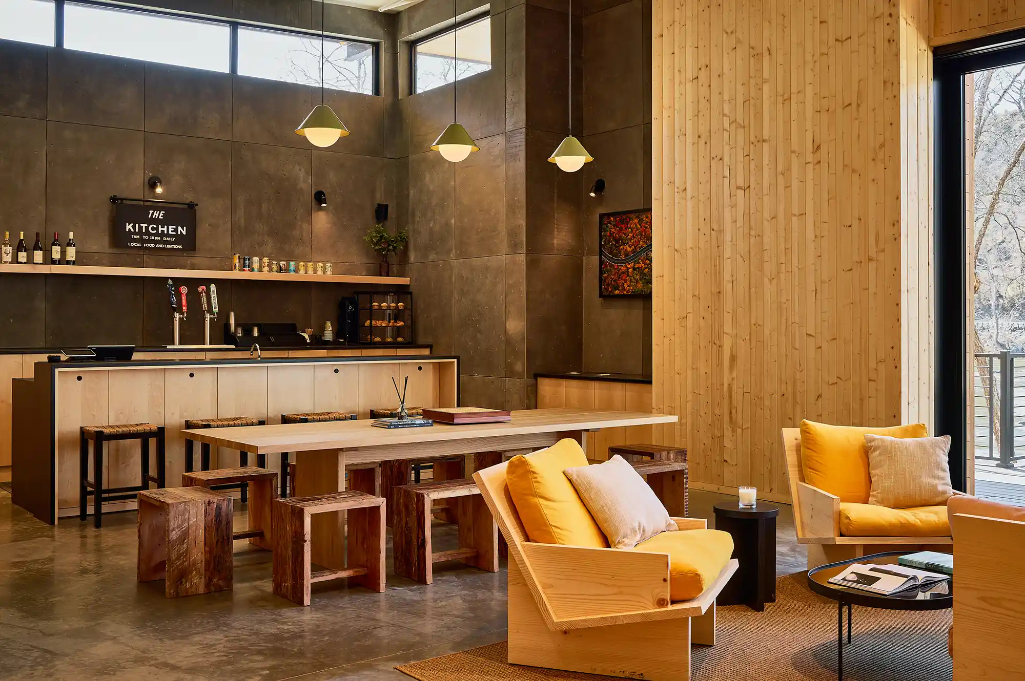 A modern lounge and kitchen area inside the AutoCamp facility with high-end bar stools and wooden accents.