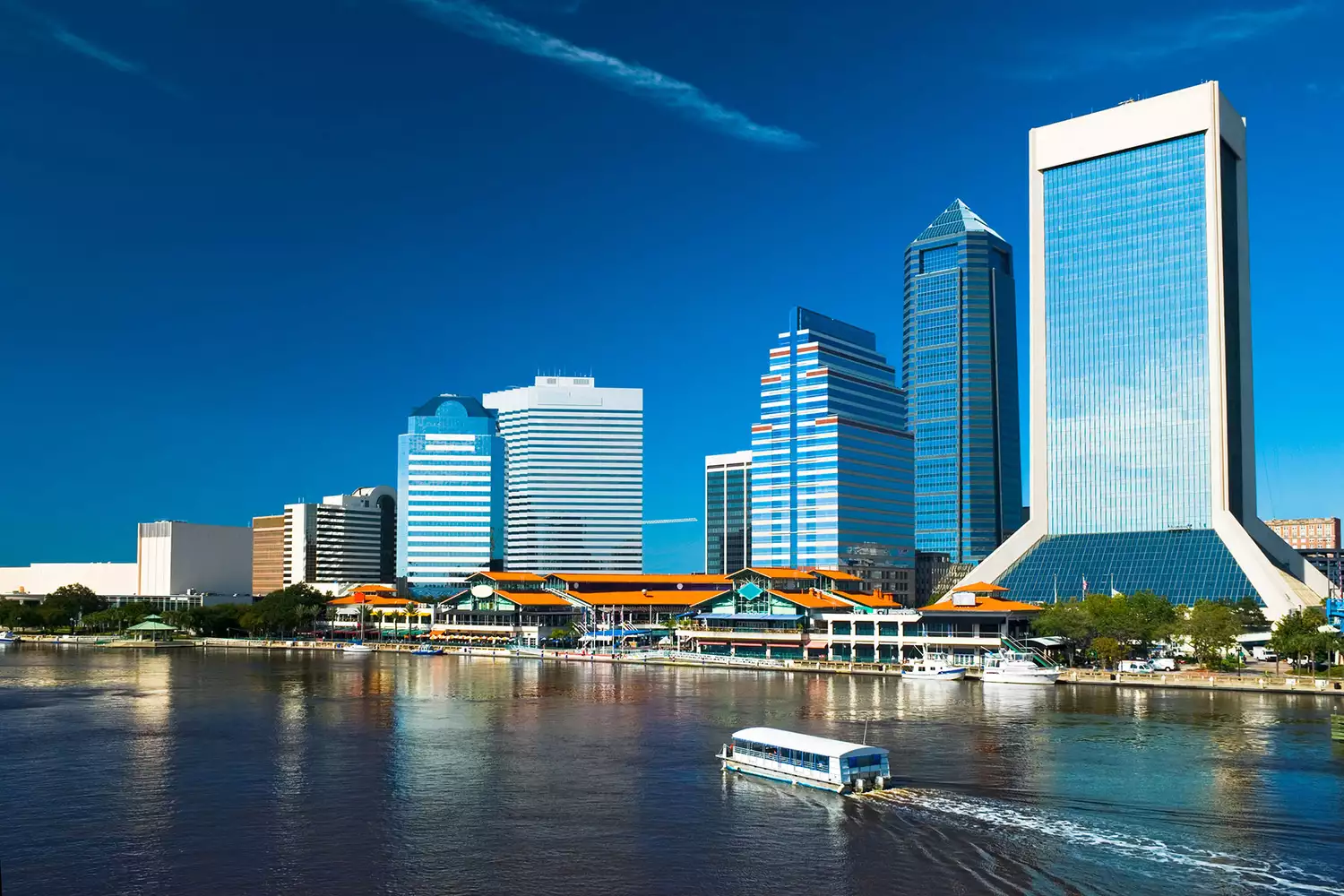 A cruising boat on the St. Johns River with the Jacksonville city skyline visible in the background.