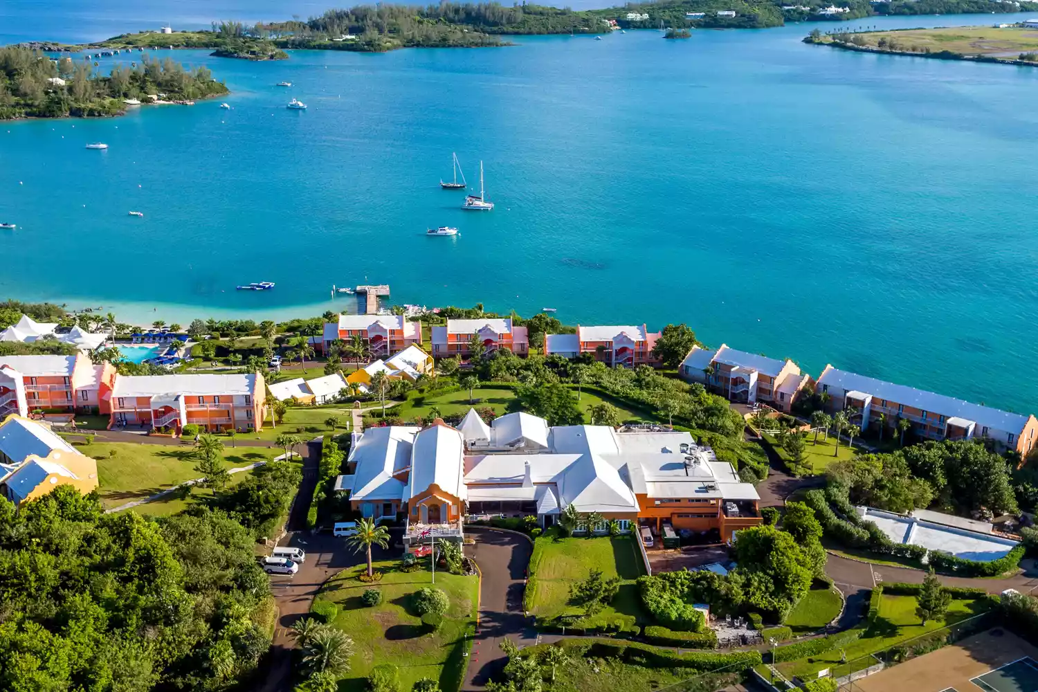 High-angle aerial shot of Grotto Bay Beach Resort showing the shoreline and lush landscaping.