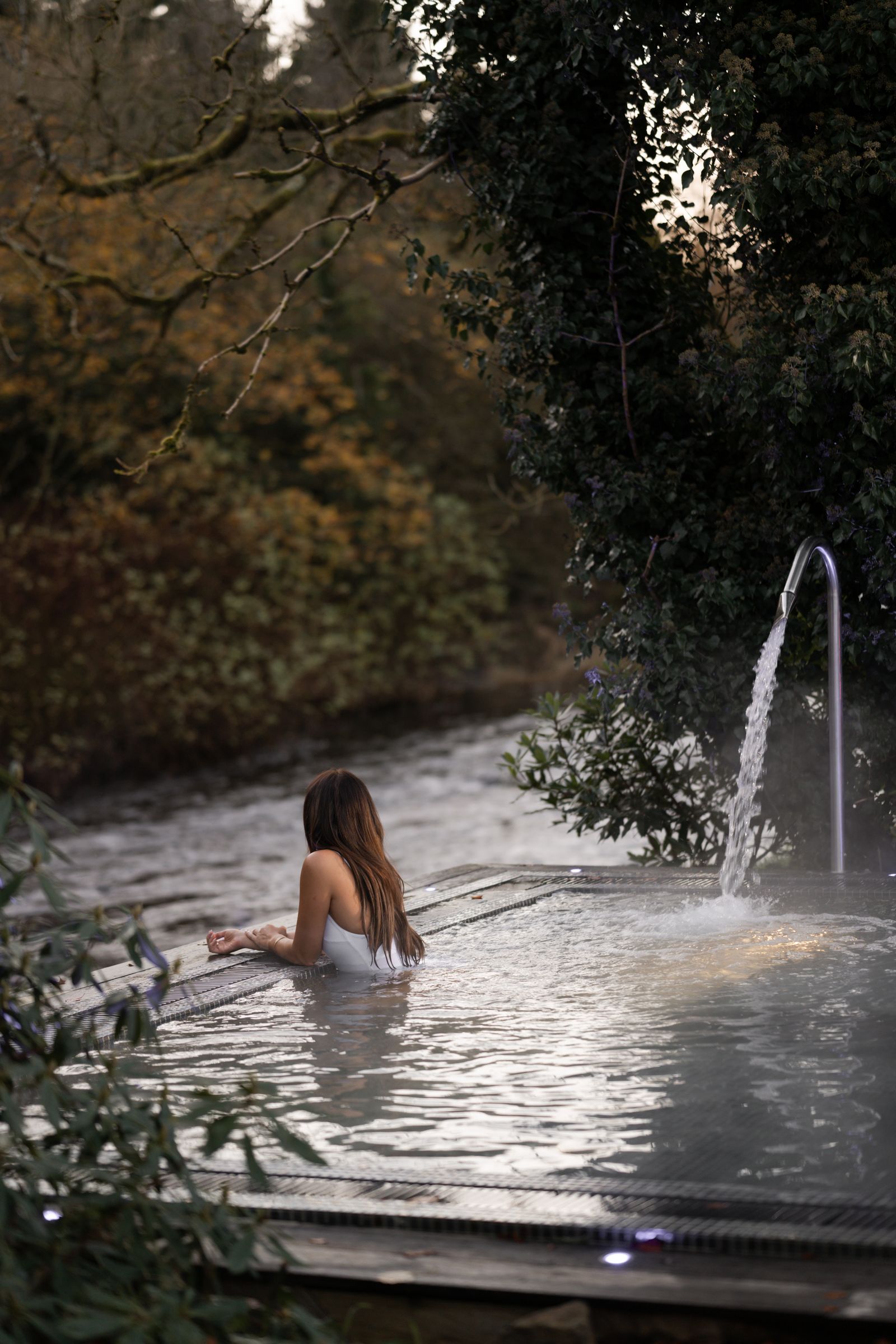 A person relaxing in a traditional copper or wooden bathtub.