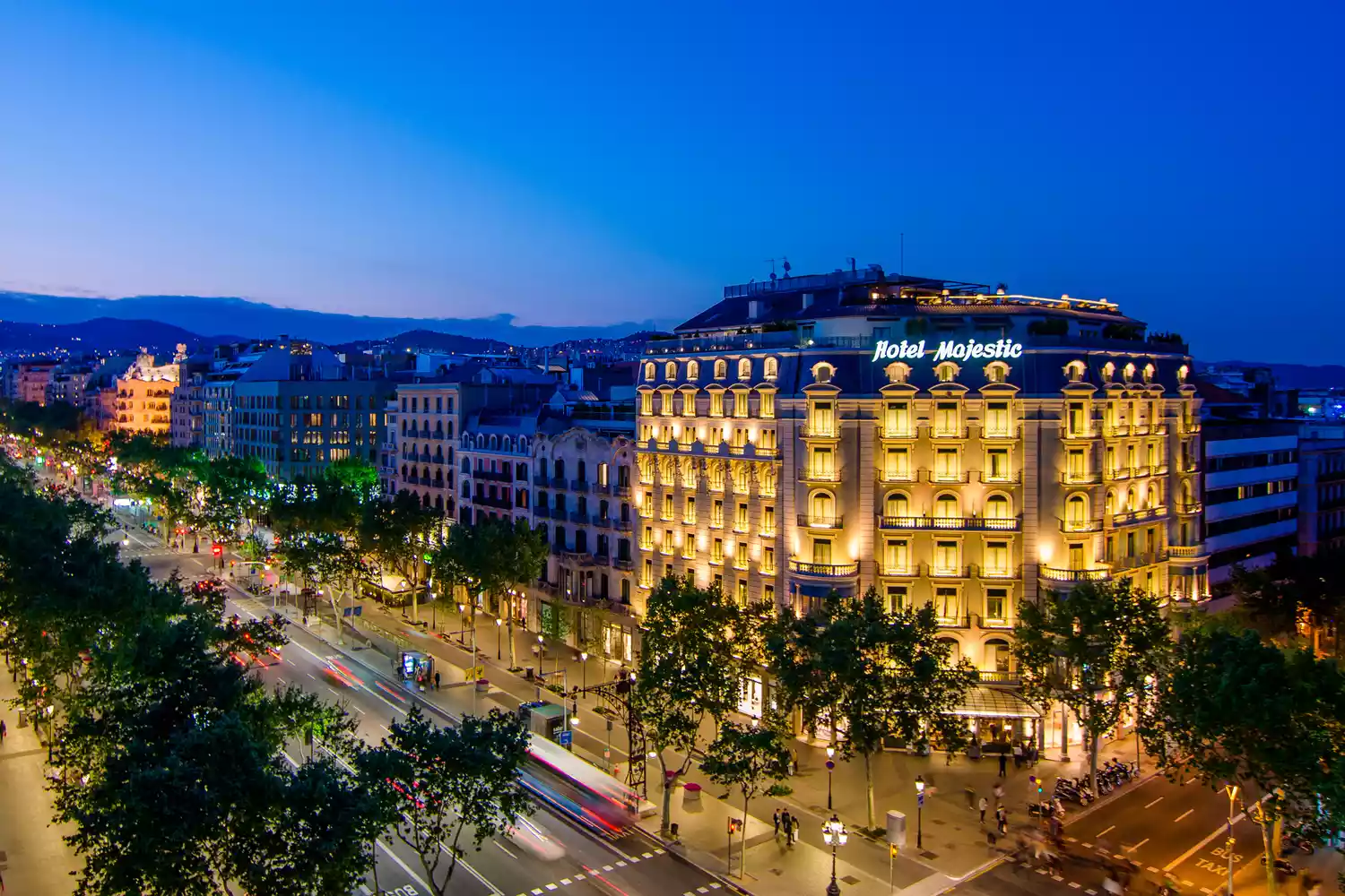 The illuminated neoclassical facade of Majestic Hotel & Spa Barcelona at night on Passeig de Gràcia.