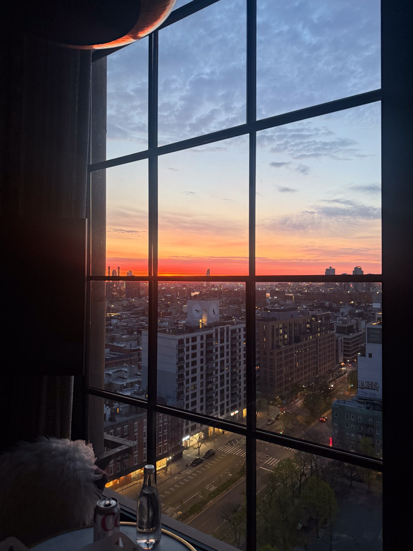 View of the New York City skyline and Lower East Side buildings through a large guest room window.