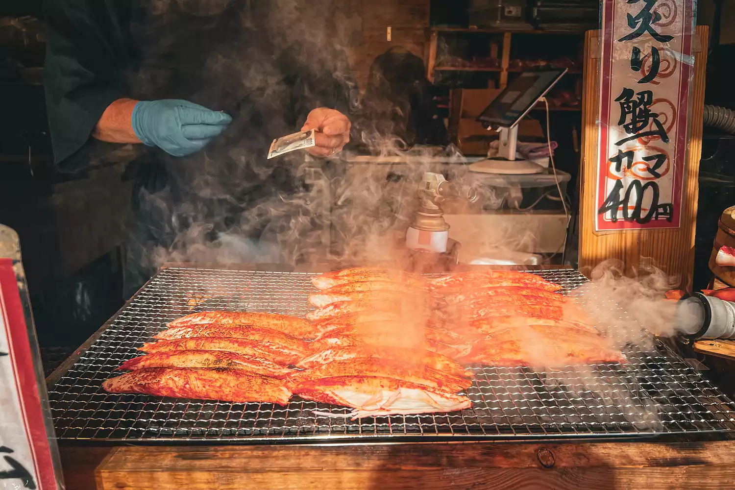 A close-up of a chef's hands carefully preparing food in a traditional Japanese kitchen environment.