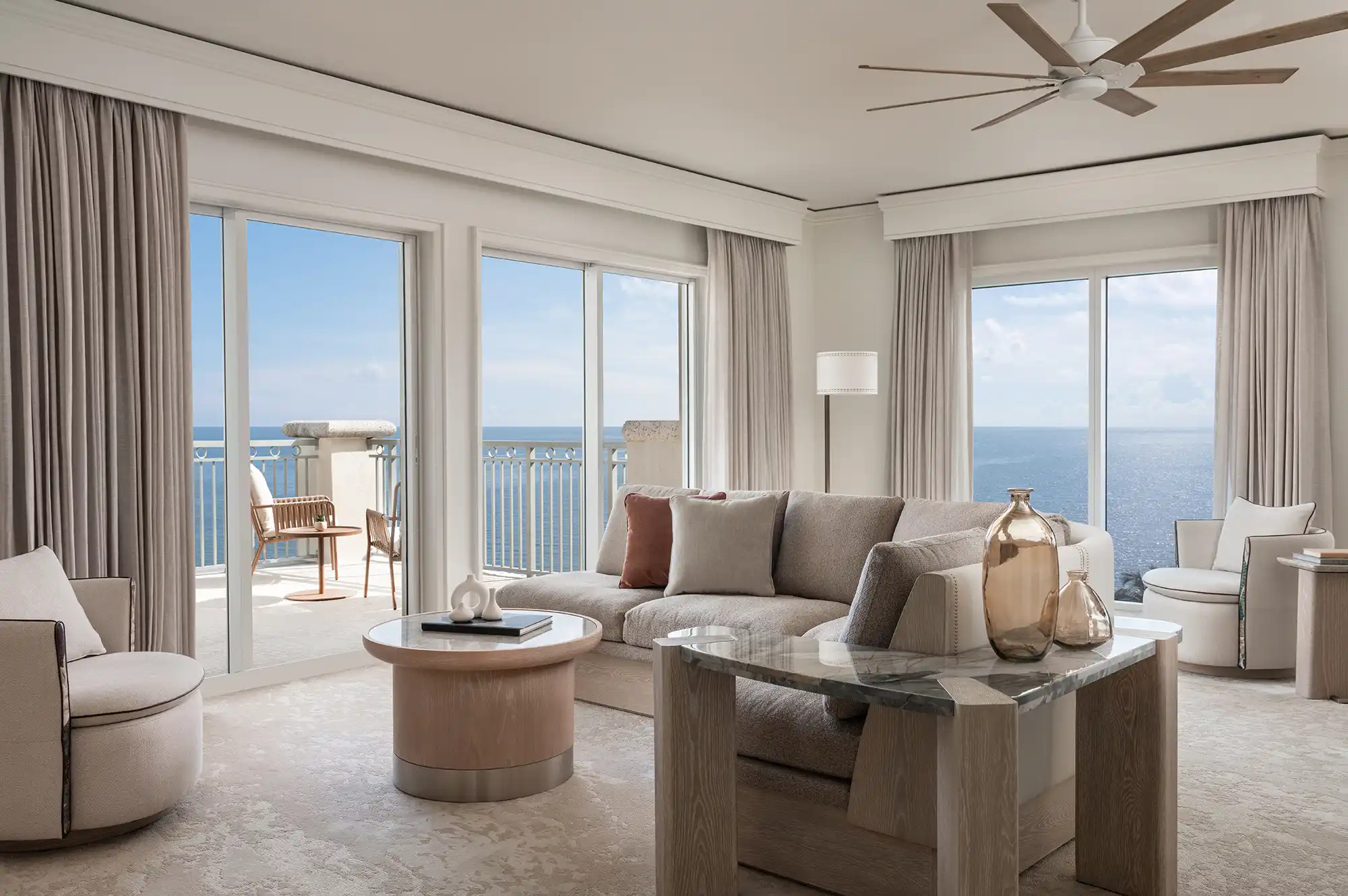 A luxurious residential suite living room with floor-to-ceiling windows and contemporary coastal decor.