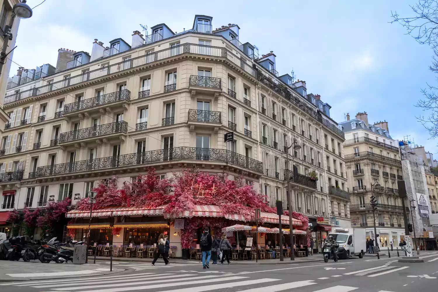 A traditional Parisian building in the Marais adorned with vibrant pink flowers.