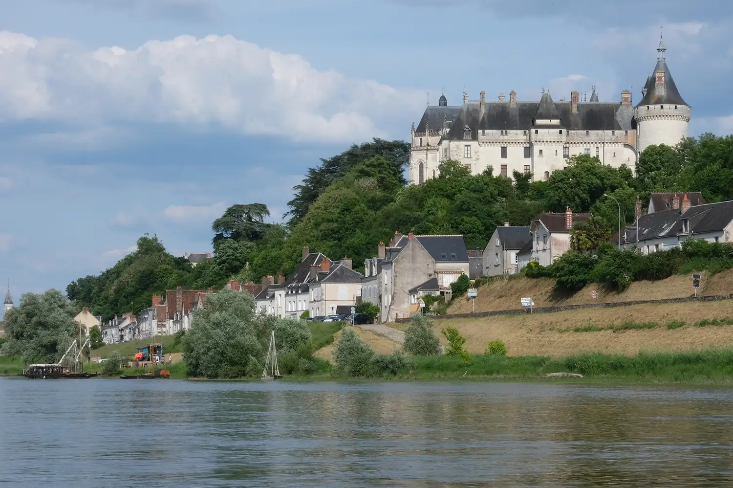 The exterior of the Château de Chaumont overlooking the Loire River under a clear sky.