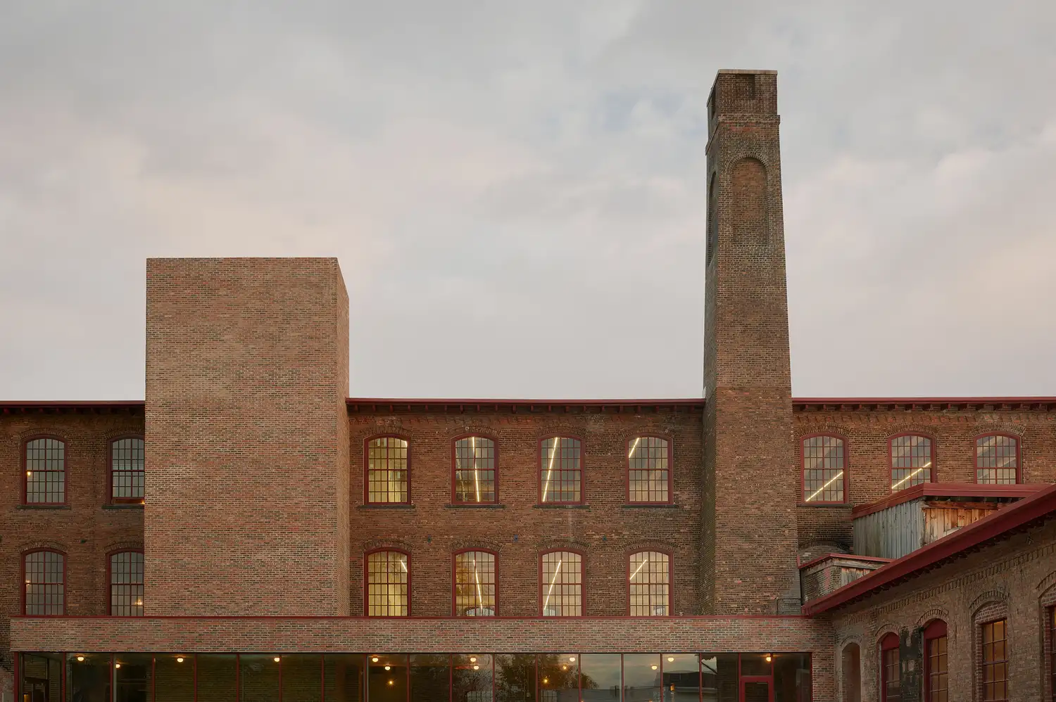 Exterior view of the historic red brick factory building with a tall chimney at Pocketbook Hudson.