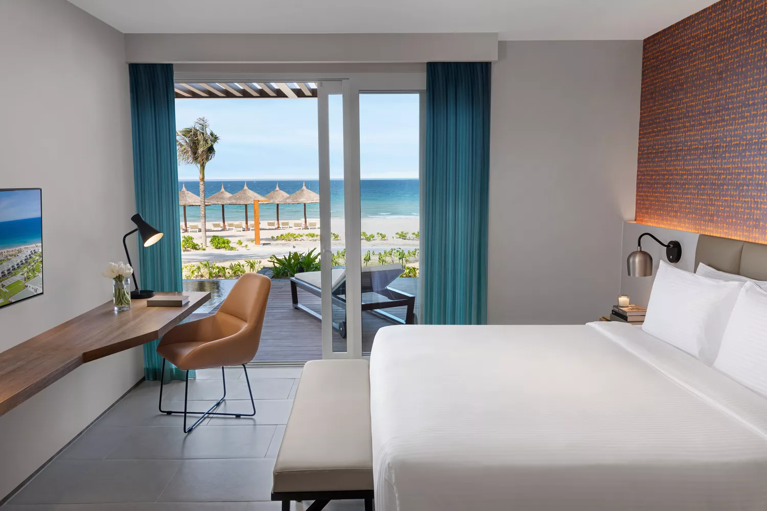 Sun-drenched modern guest room at Alma Resort with a view of the resort grounds and ocean.