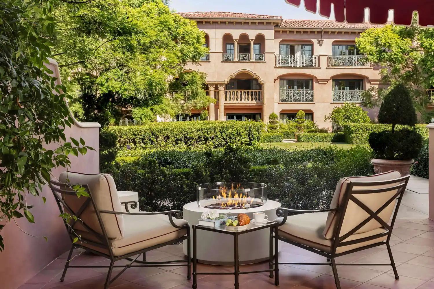 A luxury hotel courtyard with a private patio, fire feature, and manicured landscaping.
