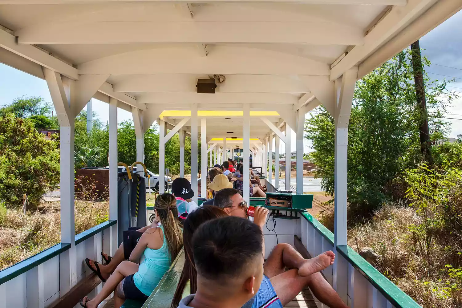 Passengers enjoying a train ride in open-air cars along the West side of Oahu.