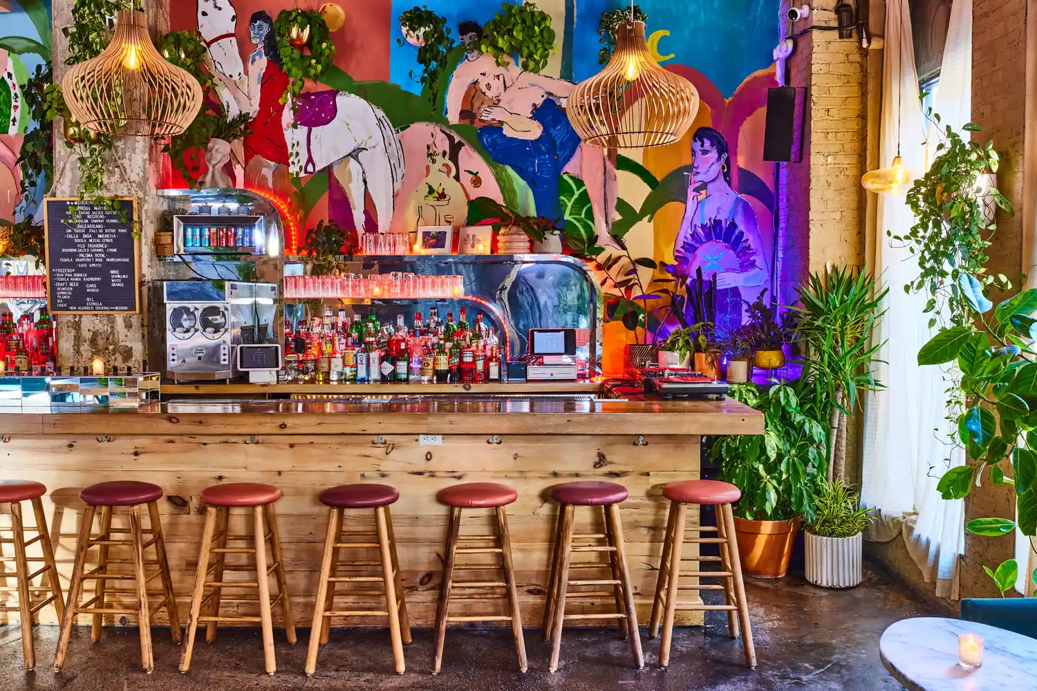 Colorful artistic mural and bar stools inside a trendy Williamsburg establishment.
