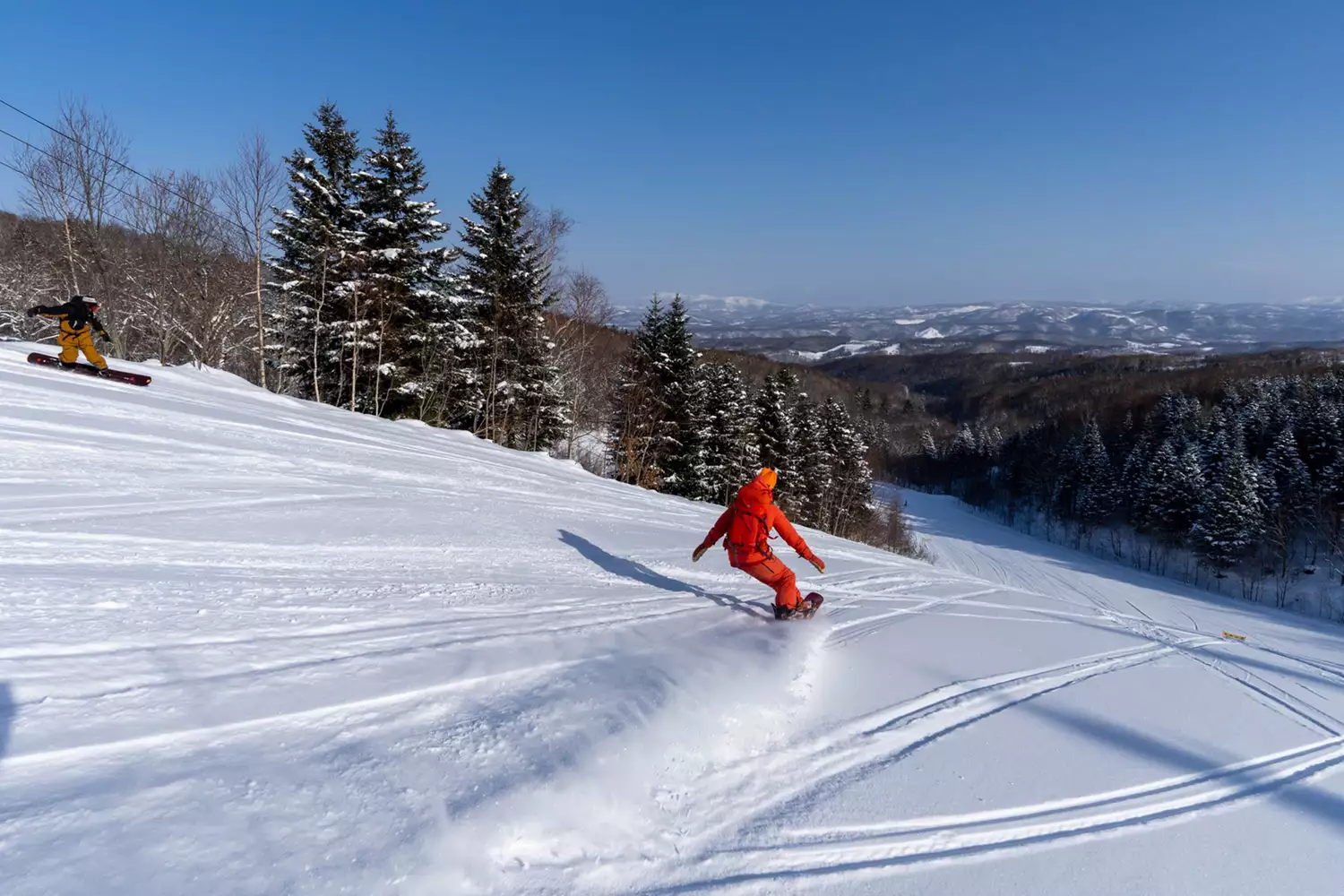 A snowboarder surrounded by a cloud of light powder snow at Rusutsu Resort in Japan.