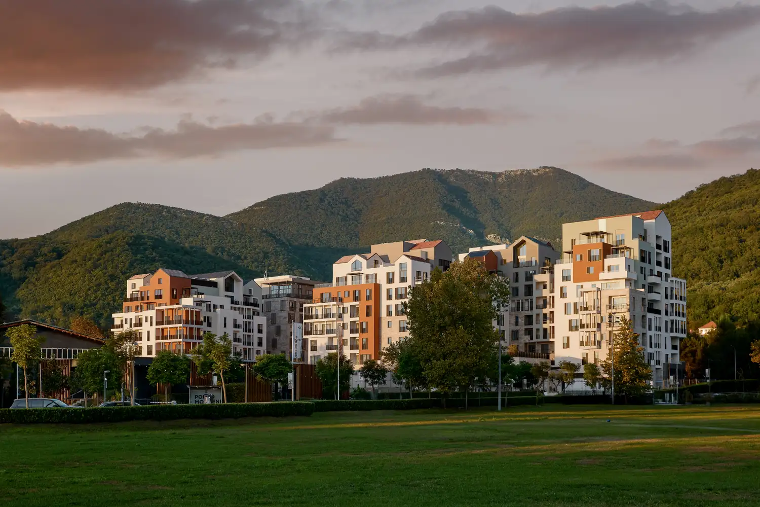 Modern hotel buildings with clean white lines set against a dramatic mountain range.