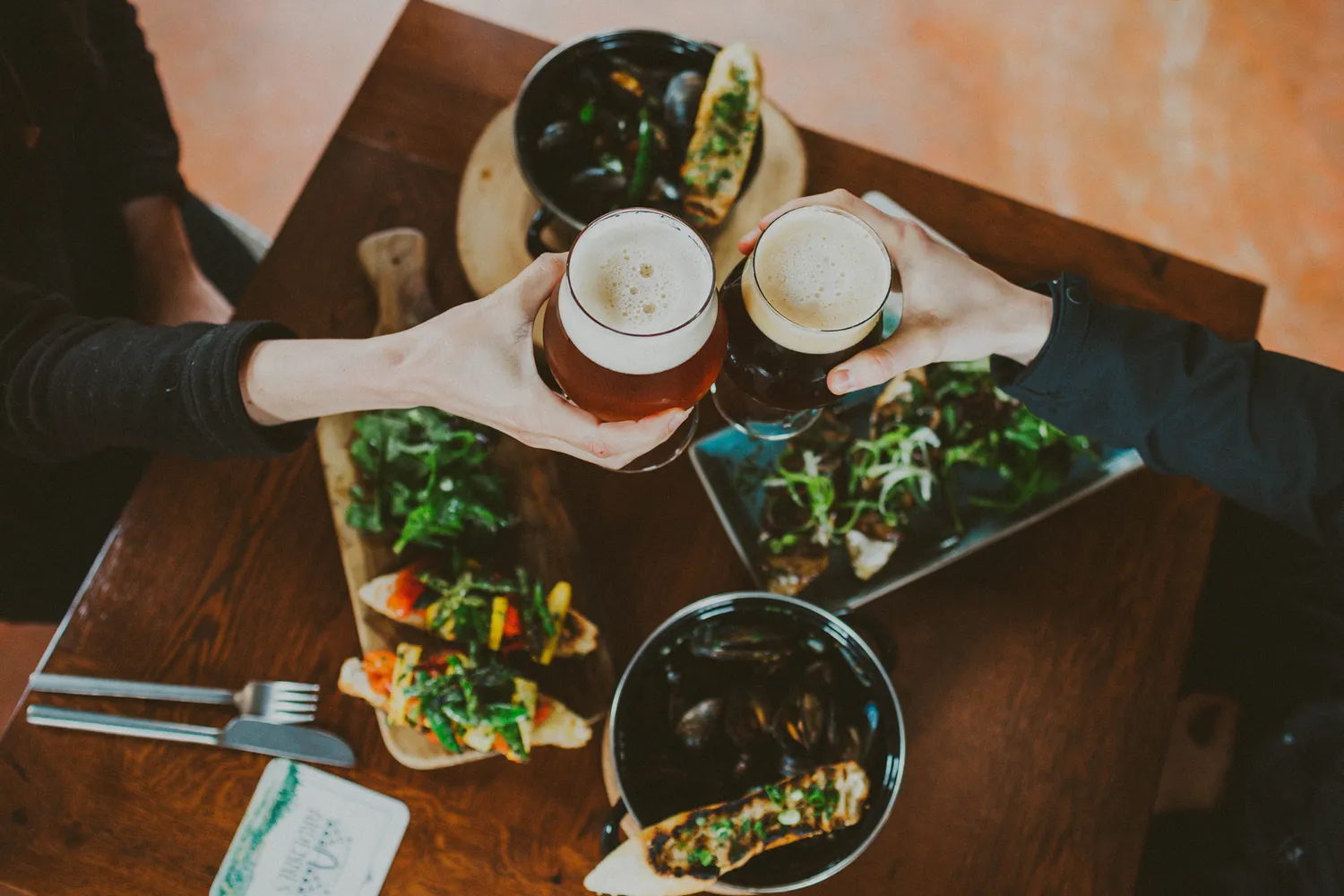 Close-up of patrons clinking glasses over gourmet food at a local Geneva establishment.